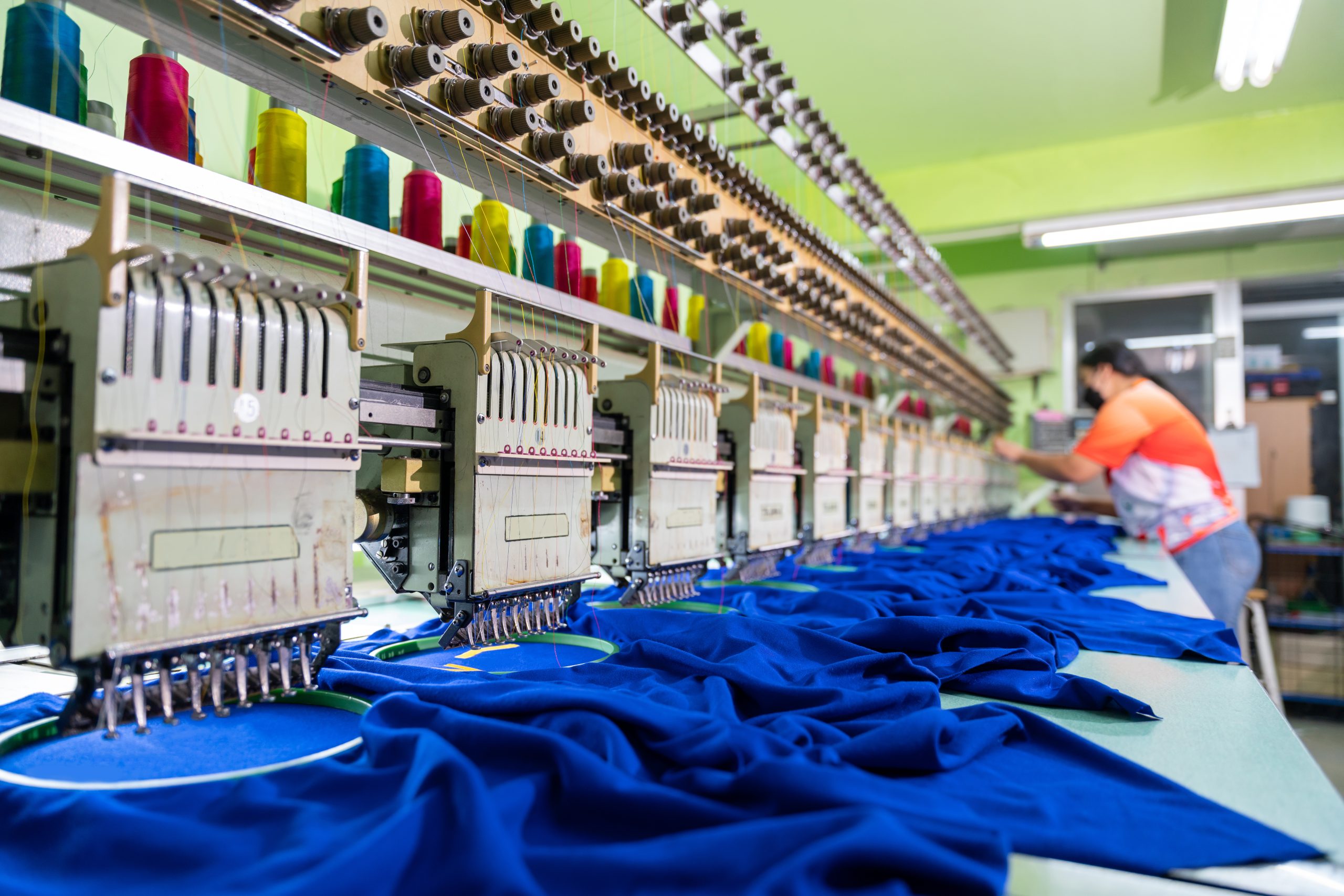 A worker working with sewing machine, Embroidery area in textile factory in industrial zone with modern machinery and technology systems. select focus of sewing machine.